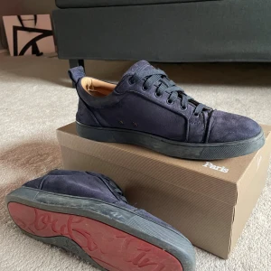 Mörkblåa Christian Louboutin - (Allt OG finns dvs kvitto, dustbag m.m) Säljer ett par mörkblå sneakers från Christian Louboutin i mocka med klassisk röd sula och svarta snören. Skorna har rund tå, platt sula och snygga detaljer i skinn på insidan. Perfekta för dig som vill ha något unikt och stilrent. 
