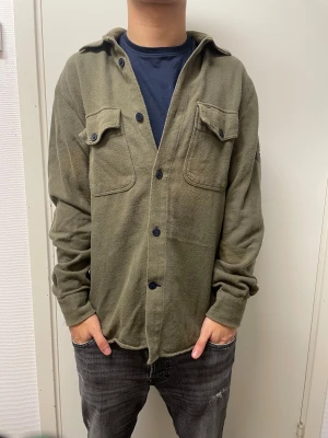 Overshirt från Tommy Hilfiger - Snygg olivgrön Overshirt från Tommy Hilfiger. Mycket bra skick. Modellen är 173cm, 64kg. Pris kan självklart diskuteras!