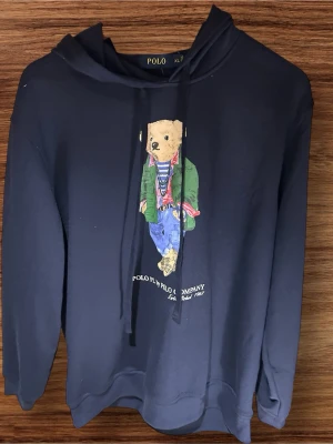 Polo Bear Hoodie - •	Polo Bear Hoodie till salu 🐻🧥 	•	QR-koden ser konstig ut pga att butikspersonalen rev av en del av lappen — kvitto finns (se sista bilden) 🙏 	•	100% äkta, helt oanvänd 	•	Perfekt julklapp 🎁 / bra nu i vinter ❄️ 	•	Storlek: XL (sitter mer som L) 	•	Fråga gärna om något — svarar snabbt! 😊 	•	/ Freshfits.123