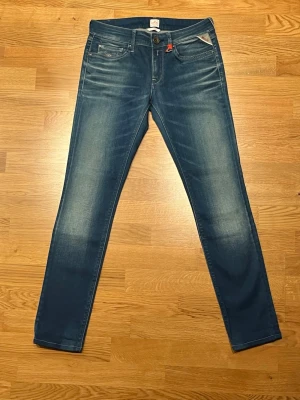 Replay jeans - Snygga blå Replay jeans med skinny fit och klassisk femficksdesign. Jeansen har en lätt tvättad look och detaljer som logga på fickan och bakfickor med dekorativa sömmar. Perfekta för dig som gillar en smal siluett och stilren denim.