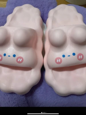 Söta rosa kanin tofflor sandaler  - Unika sandaler i ljusrosa med gulligt ansikte framtill, blå och rosa detaljer och vågig form. Tillverkade i syntetmaterial med platt sula och mönstrad undersida för extra grepp. Perfekt för dig som gillar kawaii-stil och vill sticka ut.