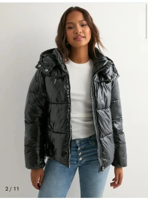 Svart jacka från Nelly - Säljer en svart, glansig pufferjacka med stor vadderad huva och dragkedja framtill. Köpte den för ca 3 månader sen. Ställ gärna frågor om du undrar nåt☺️