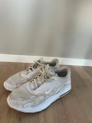 Nike Air Max vita sneakers - I gott skick, behöver bara tvättas. Nike Air Max sneakers i helvitt med mesh och syntetpaneler. Snygg, chunky sula med synlig Air-enhet och klassisk Nike-logga på sidan. Rund tå och snörning framtill. Perfekt för dig som gillar sportig och clean stil.