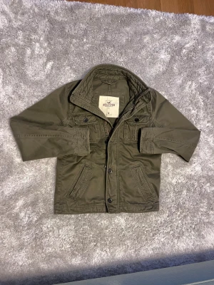 Olivgrön jacka från Hollister - Riktigt fet grön jacka från Hollister. Hollister loggan är borttagen men är annars i väldigt bra skick! 