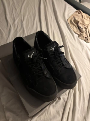 Svarta sneakers från Giuseppe Zanotti - Säljer ett par svarta sneakers från Giuseppe Zanotti med coola dragkedjor på sidorna och signaturlogga på plösen. Skorna är i skinn och textil, har snörning och en chunky platt sula. Perfekta för dig som gillar streetstyle och exklusiva detaljer. Har box och kvitto. Säljer dessa för att dom är för små och det ända felet med dem är att skinet har gått upp på sidan. Pris kan diskuteras skriv vid minsta fundering !