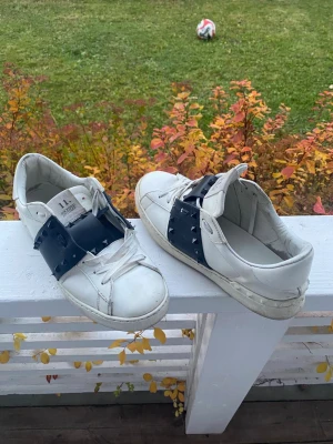 Valentino Rockstud vita sneakers - Säljer ett par vita Valentino Rockstud sneakers med svart band och ikoniska nitar över vristen