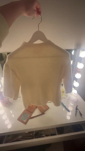 Vit stickad tröja från Gina Tricot - Mysig vit stickad tröja från Gina Tricot i storlek 170. Tröjan har en enkel design med rund hals och korta ärmar, perfekt för lager-på-lager. Den är fluffig och har en mjuk känsla som gör den superbekväm att bära.