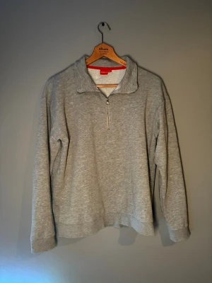 Grå half zip tröja från RYVLS - Mjuk och skön grå tröja från RYVLS med half zip framtill. Tröjan har lång ärm och en hög krage som går att öppna med dragkedja. Insidan är fleecefodrad för extra komfort och värme. Perfekt för chill dagar eller när du vill ha något enkelt men snyggt.