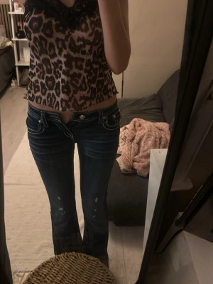 Botcut jeans miss me - Säljer ett par mörkblå botcut miss me jeans med låg midja och vita kontrastsömmar. Baktill har de snygga broderade fickor med pärldetaljer och mönster. .