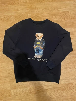 Mörkblå Polo Bear tröja ralph lauren  - Svart långärmad tröja från Polo Ralph Lauren som står  storlek L  men passar storlek S. Skitfet tröja och passar bra till vintern.  Kan gå ner i pris vid snabbt köp
