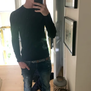 Svart långärmad tröja från Uniqlo - En stilren svart långärmad tröja från Uniqlo i storlek M. Tröjan har en klassisk rund halsringning och är tillverkad i ett mjukt, stickat material som sitter snyggt och passar perfekt till jeans. Enkel och clean look för dig som gillar minimalistisk stil.