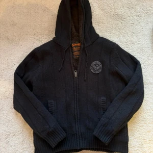 Svart stickad hoodie - Svart stickad hoodie från Schott NYC med teddyfoder inuti. Tröjan har en perfekt luva. Perfekt för kyliga dagar nu till hösten. M men sitter mer som S!