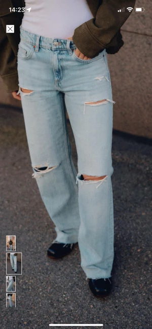 Ljusblå ripped wide jeans strl 34 - Säljer ett par ljusblå jeans med bred passform och slitna detaljer över knän och lår. Jeansen har klassisk femficksdesign, hög midja och är tillverkade i bomull. Perfekta för en avslappnad och trendig look.