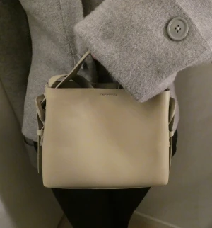 Väska  - Liten väska i snygg ljus grön färg, har både ett långt band och ett kort handtag