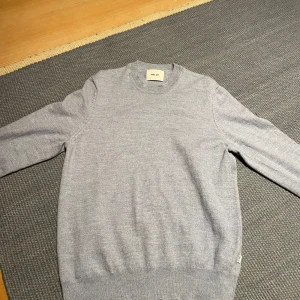 Ljusblå stickad tröja från NN07 - Snygg ljusblå stickad tröja från NN07 med rund hals och ribbade muddar. Perfekt för dig som gillar enkel och stilren design. Tröjan har lång ärm och är gjord i mjukt material som känns skönt mot huden. Passar dig som vill ha en klassisk look.