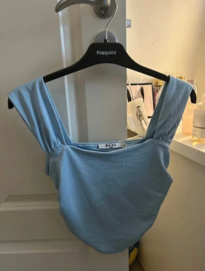 Ljusblå linnetopp från NA-KD - Säljer en ljusblå linnetopp från NA-KD i storlek M. Toppen har breda axelband och ärmlös design med mjuk, slät yta. Perfekt för dig som gillar enkel och stilren look med en touch av färg. Materialet känns lätt och bekvämt mot huden.