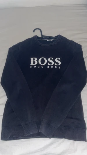 Svart stickad tröja Hugo Boss  - Svart stickad tröja från Hugo Boss i storlek M. Den är använd ganska mycket, den är solbränd på vissa ställen därmed förklarar priset. Pris kan även diskuteras!