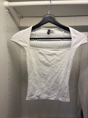 Vit croppad topp med fyrkantig hals - Säljer en vit, croppad topp med snygg fyrkantig halsringning och korta ärmar. Toppen är slim fit och gjord i mjuk bomull som sitter skönt mot kroppen.  Storlek xss, passar xss-s ungefär. Från H&M
