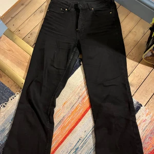 Svarta jeans med bootcut  - Snygga svarta jeans med klassisk femficksdesign och lite vida ben. Jeansen har hög midja. Passar perfekt till sneakers eller boots och har en stilren look. Från H&M. Använda många gånger.