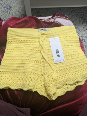 Gula stickade shorts - Superfina ljusgula stickade shorts med snörning i midjan och söt volangkant nedtill. De har ett genombrutet mönster och är fodrade med mjuk bomull på insidan. Perfekta för sommarens chill dagar! Nypris 179☺️