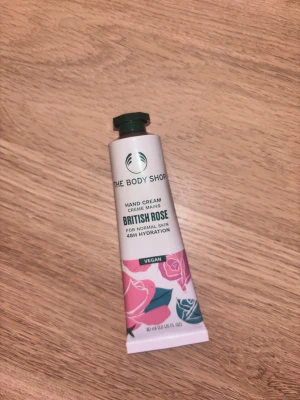 The Body Shop British Rose handkräm - Handkräm från The Body Shop i doften British Rose. Tuben är 30 ml och tillverkad av återvunnen aluminium. Designen är vit med rosa och blå rosor, grönt lock och veganmärkning. Ger 48 timmars återfuktning och passar normal hud. Helt ny (oanvänd). Fick i julkalender 2025. Säljare för att gillar inte ros doft. 
