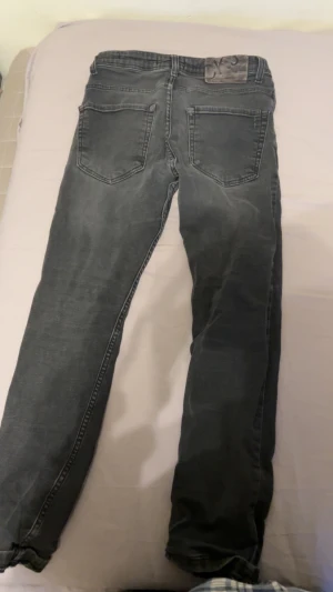 Svarta straight jeans från Calvin Klein - Säljer ett par svarta jeans från Calvin Klein med klassisk femficksdesign och logopatch bak. Jeansen har rak passform och är tillverkade i mjukt denimtyg med lätt tvättad look. Perfekt för dig som gillar stilrena och tidlösa jeans.