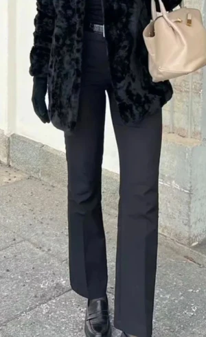 Bikbok Vilma kostymbyxor - Snygga svarta kostymbyxor med bootcut-snitt och hög midja. Byxorna har en klassisk rak passform och är perfekta för en stilren look. Materialet är slätt och ger en dressad känsla. Passar dig som gillar att klä dig trendigt och elegant.