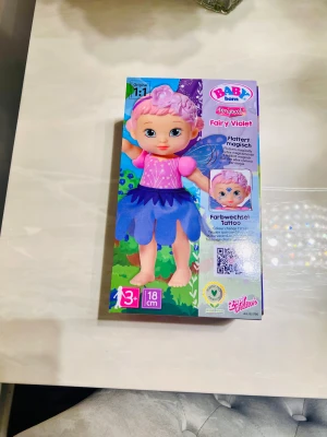 Baby Born Fairy Violet klänning - Helt ny                                                                              BABY Born Storybook – Fairy Violet (Ny/Oanvänd) Helt ny docka, aldrig öppnad. Vingarna rör sig magiskt och den har färgskiftande tatuering. Perfekt för barn 3+. Nypris 399 kr – mitt pris 120kr.