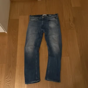 Blå Replay Rocco jeans  - Säljer ett par snygga Replay Rocco jeans i klassisk blå tvätt med slitningar och raka ben. Jeansen har fem fickor, komfortabel passform och tydliga Replay-detaljer vid fickorna. Perfekt för dig som gillar en avslappnad men stilren look. Pris kan diskuteras😄