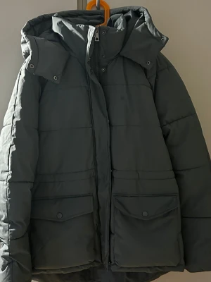 Grön  pufferjacka  -  Jackan har dragkedja och tryckknappar, perfekt för kalla dagar. Den quiltade designen ger en schysst look och extra värme.