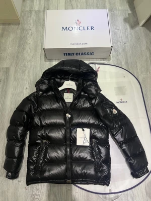 Moncler maya jacka - Hej! Jag säljer nu min svarta moncler maya. Den är i jättebra skick andvänt väldigt lite och sparsamt den har inga defekter eller liknande. Jackan har dun i sig så den är perfekt till den kalla hösten/vintern. Den är äkta och köpt på monclers hemsida inte så länge sedan. Jag säljer jackan pågrund av att jag inte har tid att andvända den då jag mest har jobbklädder på när jag jobbar. De ingår med dustbag, lapparna. Jackan är i size 2 i moncler. Hör av dig vid frågor och extra bilder!