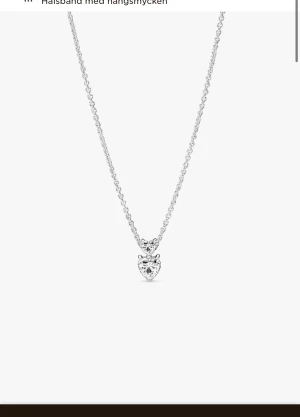 Silverhalsband med hjärthänge från Pandora - Ett stilrent halsband i silver från Pandora med ett gnistrande hjärta som hänge. Kedjan är tunn och elegant, och hjärtat är dekorerat med en klar sten som ger extra bling. Perfekt för dig som gillar romantiska detaljer och vill ha något som sticker ut.