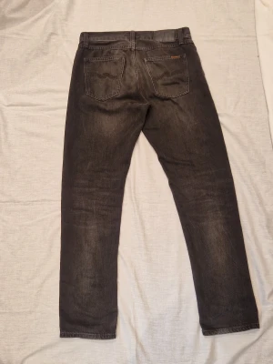 Svarta Nudie Jeans - Tjena säljer ett par riktigt snygga Nudie Jeans🙌🏻 De har en riktigt snygg passform och passar 28/30 och 30/32 perfekt✌🏻Använda ett fåtal gånger det vill säga väldigt bra skick och inga defekter. Hör av dig vid funderingar✅ Nypris 1600:-
