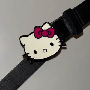 Hello Kitty Svart Buckle Belt/Bälte - Svart Hello Kitty bälte, knappt använt så i bra skick <3 Skriv ifall du vill ha mått, den är justerbar och det går att göra fler hål  