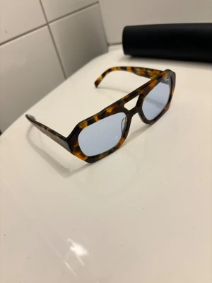 Vehla River Solglasögon  - Snygga glasögon med turtlemönstrad båge i bruna och beige toner. Glasen är svagt blåtonade