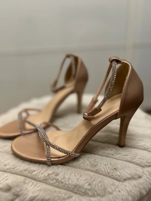 Rose’guld  klackskor 36 - Säljer ett par helt nya, oanvända roseguld klackskor i storlek 36 som är riktigt fina och eleganta. Skorna har en lyxig roseguldfärg som passar perfekt både till fest och speciella tillfällen.  Storlek: 36  Hälhöjd: 8,7 cm  Fotlängd: 23 cm  Omkrets fottopp: 21 cm