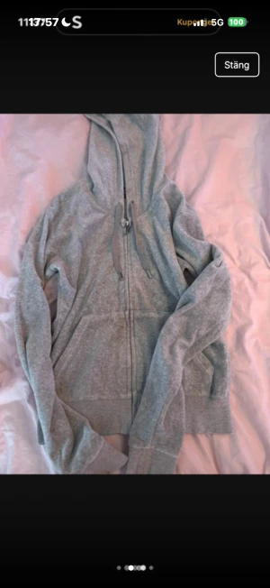 Grå hoodie från Juicy Couture - Mysig grå hoodie från Juicy Couture med dragkedja och snörning vid huvan. Tröjan har långa ärmar och praktiska fickor framtill. Perfekt för chill dagar och enkel att matcha med jeans eller mjukisbyxor.