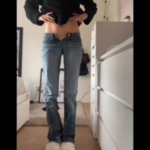 Levis ljusblå bootcut jeans - Midjemått rakt över: 36 cm Innerbenslängd: 82 cm. Ljusblå Levis jeans med bootcut passform och låg midja. Klassisk femficksmodell i jeansmaterial med snygga slitningar och Levis-logga på bakfickan. Perfekta för dig som gillar en avslappnad och trendig look. Obs gylfen är loss men går att fixa enkelt 