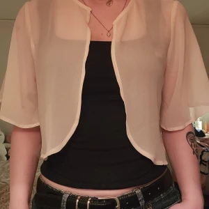 Beige transparent bolerotopp - Tunn och flowy beige bolerotopp med korta, luftiga ärmar och öppen front.