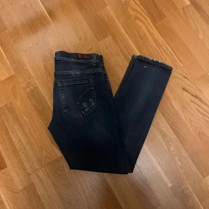 Dondup George  - Snygga Dondup jeans i mörkblå tvätt med diskreta slitningar och stänkdetaljer. Skön passform, klassisk femficksdesign och orangea kontrastsömmar. Ikonisk Dondup logotyp på bakfickan. Perfekt för dig som gillar stilrena jeans med lite edge.