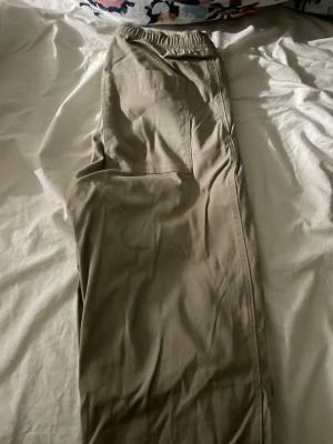 Beige cargopants med resårmidja - Säljer ett par beige cargopants med resår i midjan och stora sidofickor. Byxorna har en avslappnad passform och är tillverkade i mjukt bomullsmaterial. Perfekta för en chill och avslappnad stil.