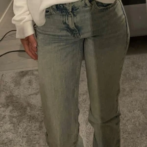 Medelmidjade utavänga jeans i ljusblå denim - Snygga medelmidjade jeans i ljusblå denim med klassisk femficksdesign. Jeansen har utsvängda ben och subtil tvätt för en trendig look. Perfekta att matcha med en hoodie eller crop top för en chill stil.