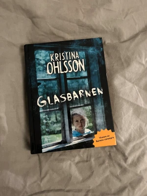 Glasbarnen - En spännande och mystisk bok om Billie som flyttar till ett nytt hus där märkliga och otäcka saker börjar hända. Tillsammans med kompisen Aladdin försöker hon ta reda på sanningen om husets mörka historia. Perfekt för dig som gillar nervkittlande berättelser!