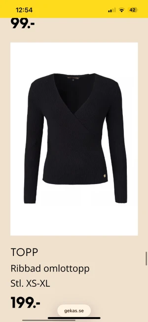 Svart ribbad omlottopp - Svart omlottopp med ribbad struktur och lång ärm. Toppens omlottdesign ger en snygg v-ringad hals och den är tillverkad i ett mjukt, stretchigt material som sitter skönt mot kroppen. Perfekt att styla med jeans eller kjol för en trendig look.