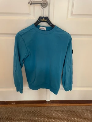 Blå långärmad tröja från Stone Island - Tjena! Säljer min snygga blå långärmade tröja från Stone Island med klassisk patch på vänster ärm. Tröjan har rund hals och är tillverkad i mjuk bomull som är skön mot huden. Storlek: junior 156/xs. Skick: 8/10. Bara att fråga om det är något! Priset går att diskutera!😊