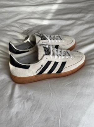 Adidas Spezial beiga sneakers - Adidas Spezial sneakers i beige mocka storlek 41 med svarta ränder på sidan. Skorna har en brun gummisula, snörning och rund tå. Dessa är även engångsanvända😊