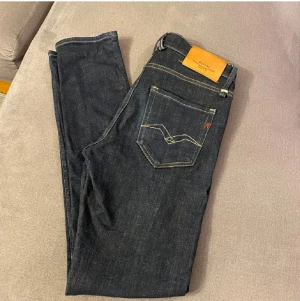 Replay Jeans - Snygga mörkblå jeans från Replay, modell MickyM med slim tapered fit. Klassisk femficksdesign, kontrastsömmar och guldfärgade nitar. Jeansen har normal midja och raka ben, tillverkade i slitstarkt jeansmaterial.