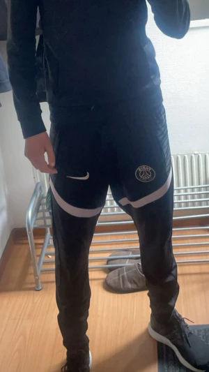 Svarta PSG träningsbyxor Nike L - Snygga fotbollsbyxor utav psg. 10/10 skick.Det står L men hade sagt att de passar M. Sitter lite pösigt på mig då jag har ganska smala ben är 184 de passar perfekt i längden. Snygga och perfekta till dig som gillar träning eller bara för hemma användning. Priset är ej hugget i sten!!!!!