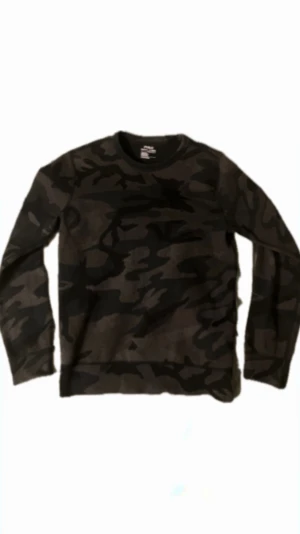 Camouflage tröja från Polo Ralph Lauren - Snygg långärmad tröja från Polo Ralph Lauren med mörkt camouflage-mönster i svart och grått. Klassisk rund hals och diskret broderad logga på bröstet. Perfekt för dig som gillar streetwear och vill sticka ut med en cool look. Tveka inte på att höra av er vid frågor!