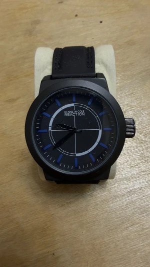 Kenneth Cole Reaction svart klocka - Snygg svart klocka från Kenneth Cole Reaction med rund urtavla och blå detaljer. Klockan har ett stilrent, modernt utseende med svart skinnarmband och silverfärgad krona. Urtavlan har tydliga markeringar och en cool grafisk design.